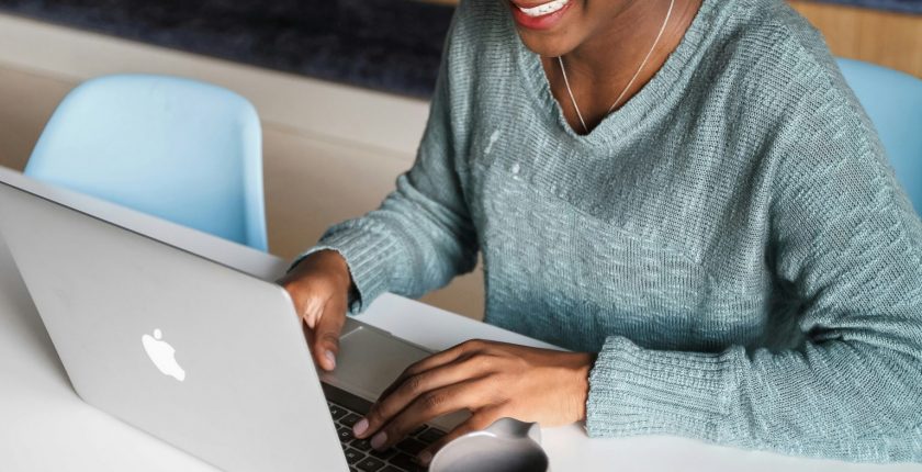Image is of a person wearing a grey top typing on a laptop